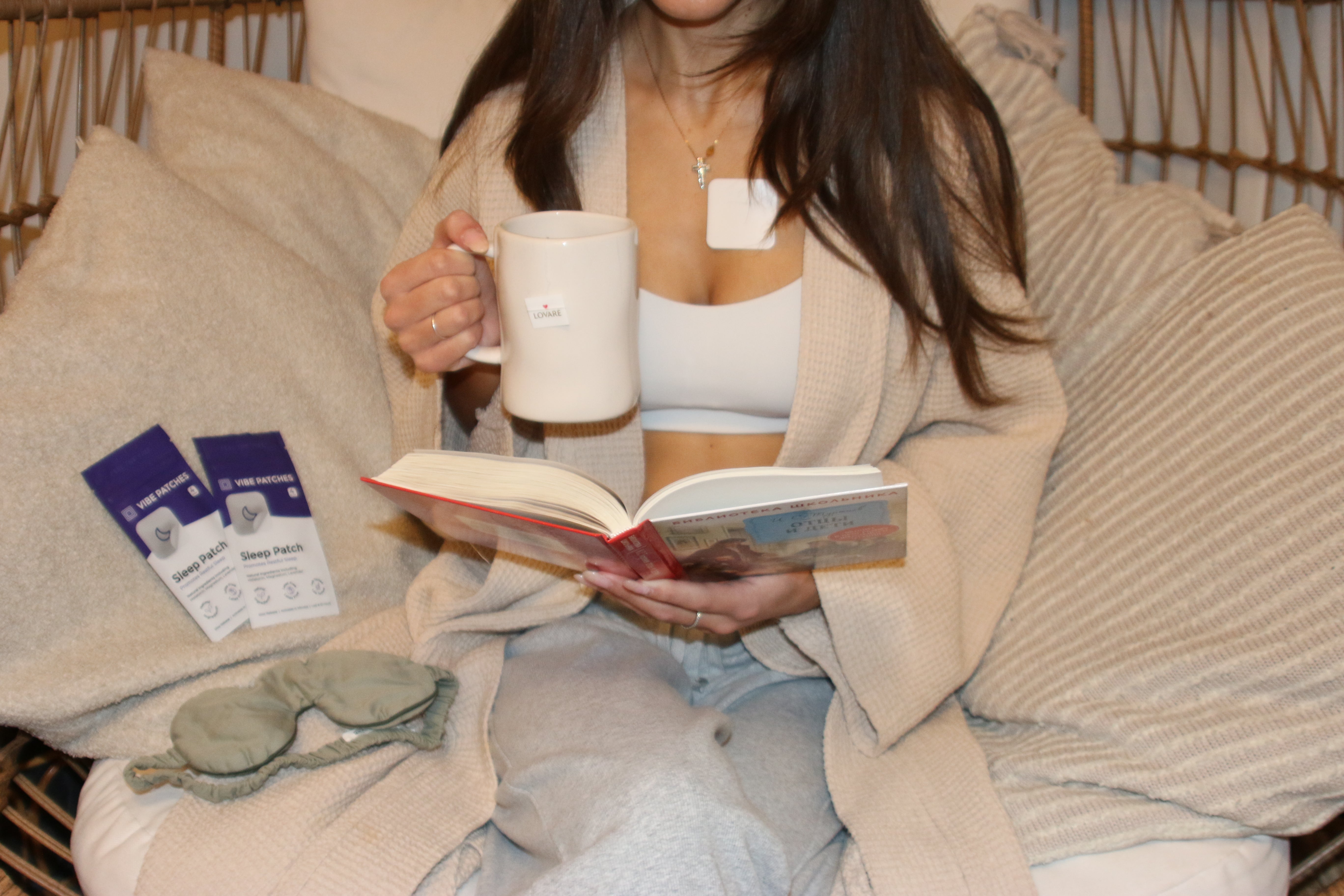 A woman sitting on a hammock drinking coffee with Vibe Patches products.